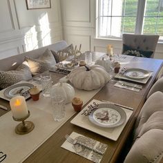 a dining room table is set with plates and place settings for thanksgiving dinner, along with candles