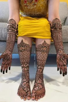 a woman sitting on top of a couch covered in hendikes and legs decorated with intricate designs