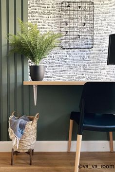 a chair sitting next to a desk with a computer on it and a potted plant