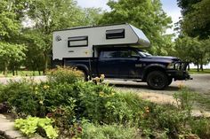 a truck with a camper attached to it parked on the side of a road