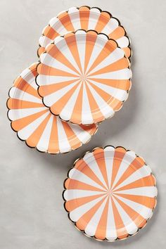 three orange and white plates sitting next to each other on top of a gray surface