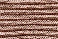 close up view of the texture of a knitted blanket with horizontal stripes in light brown