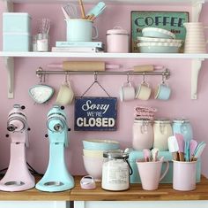 a kitchen with pink walls and shelves filled with cooking utensils, coffee mugs and other items