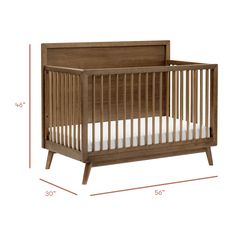 a wooden crib with white sheets and measurements