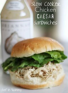 a chicken caesar sandwich with lettuce and sauce next to a bottle of cole slaw