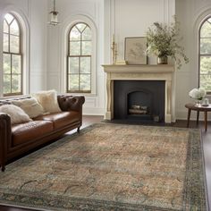 a living room filled with furniture and a fire place in front of two large windows