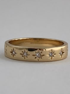 a gold ring with five stars on the side and two small diamonds in the middle