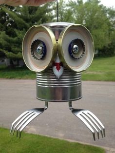 a hand holding up a tin can robot with two eyes and forks attached to it