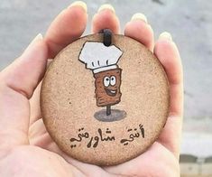 a hand holding a rock with a cartoon character on it's face and the words, i love you in arabic