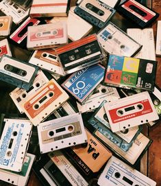 a pile of cassettes sitting on top of a wooden table next to each other