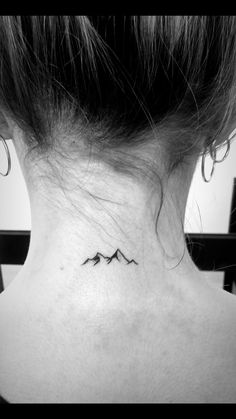 a woman's neck with a small mountain tattoo on the back of her neck