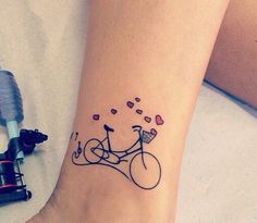 a tattoo on the foot of a person with a bicycle and hearts flying out of it