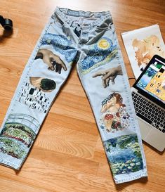 a pair of jeans with pictures on them and a lap top sitting next to it