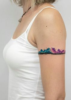 a woman wearing a white tank top with a watercolor tattoo on her left arm