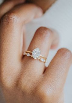 a woman's hand with a diamond ring on top of her finger and the other hand holding it