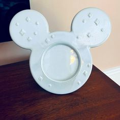 a mickey mouse shaped plate sitting on top of a wooden table next to a mirror