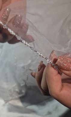 a woman holding onto a piece of plastic with glitter on it's fingers and hand