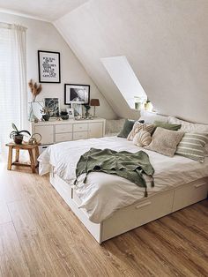 a bedroom with white walls and wooden flooring is pictured in this image, there are pictures on the wall above the bed