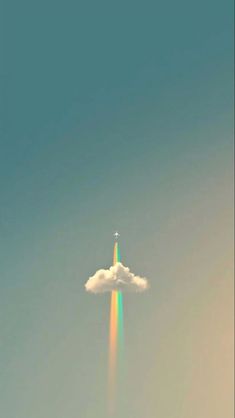 an airplane flying in the sky with a rainbow colored streak coming out of it's side