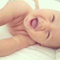 a close up of a baby laying on top of a bed with its mouth open