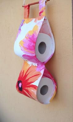 two rolls of toilet paper are hanging on the wall next to each other with flowers painted on them