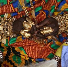 an african woman wearing gold bracelets and rings on her hands, with other accessories around her neck