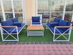 three chairs and a coffee table sitting in front of a building with glass doors on the outside