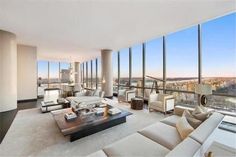 a living room filled with furniture and large windows overlooking a cityscape in the distance