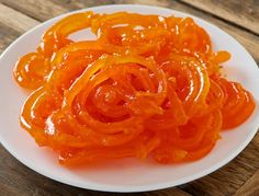 sliced orange peels on a white plate sitting on a wooden table top, ready to be eaten