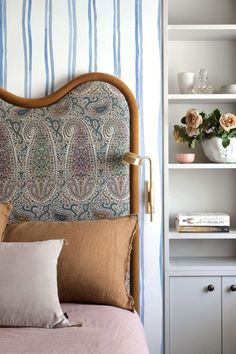 a bed with a headboard and pillows on it next to a book shelf filled with books