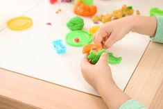 a child is playing with plastic toys on the table in front of other play doughnuts