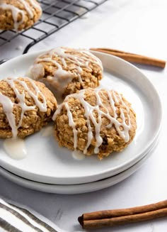 three cinnamon roll breakfast cookies on a white plate with icing drizzled