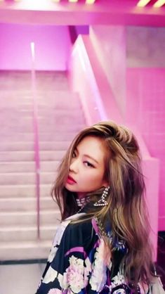 a woman with long hair standing in front of stairs