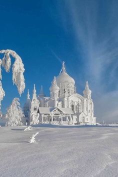 a large white building sitting in the middle of a snow covered field under a blue sky