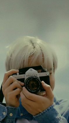 a young boy holding up a camera to take a photo with it's reflection