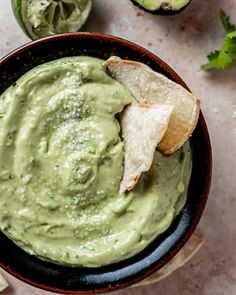 a black bowl filled with guacamole and tortilla chips on the side