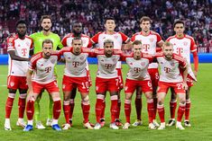 a group of soccer players pose for a team photo on the field in front of an audience