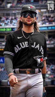 a baseball player with long hair wearing a black and gray uniform in front of a crowd