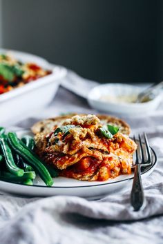 a white plate topped with green beans and lasagna