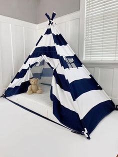 a blue and white striped teepee bed with a teddy bear