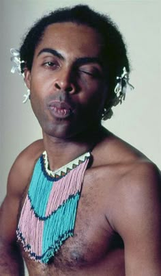 a man with no shirt on wearing a beaded necklace and earring around his neck