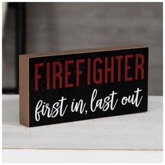 a wooden sign that says firefighter first in last out on the side of a table