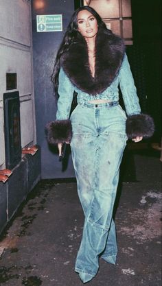 a woman walking down the street wearing jeans and fur