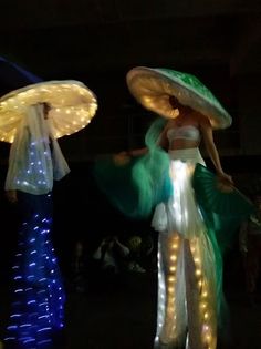 two women dressed in costumes with lights and umbrellas