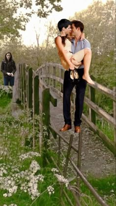 a man holding a woman on top of a wooden fence