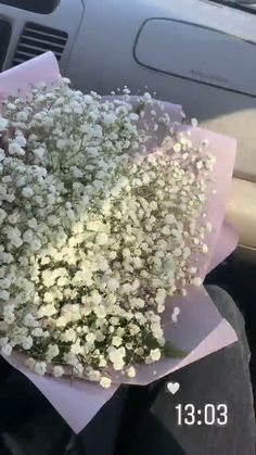 a bunch of white flowers sitting on top of a pink paper in the back seat of a car