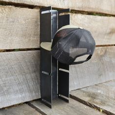 a hat is hanging on the side of a wooden wall next to a piece of metal