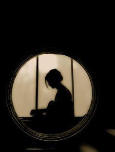 the silhouette of a person sitting in front of a window