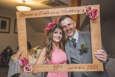 a man and woman pose for a photo in front of a table with flowers on it