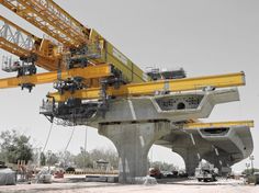 a large yellow crane sitting on top of a cement structure in the middle of construction